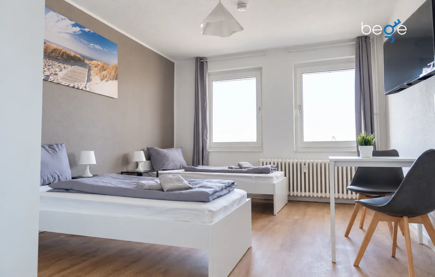 Monteurzimmer in Duisburg: zwei Einzelbetten, Tisch mit zwei Stühlen, Fernseher